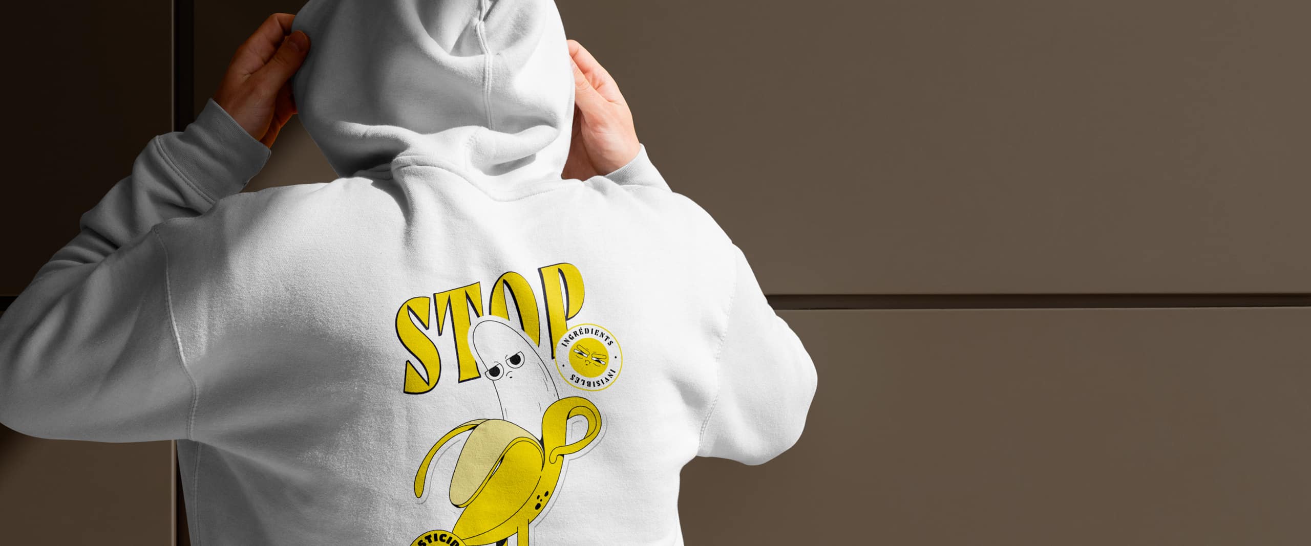 Personne portant un sweat à capuche blanc avec un motif de banane et le message 'STOP ingrédients invisibles' pour une campagne de sensibilisation de @actionaid_fr.