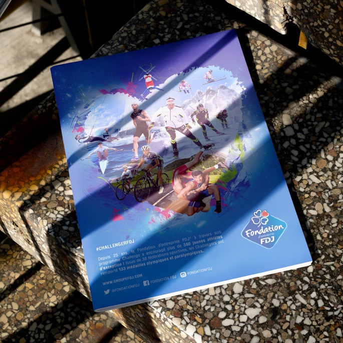 Campagne presse de la Fondation FDJ posée sur un sol pavé, mettant en avant des athlètes dans diverses disciplines sportives, pour promouvoir l'importance du sport et du développement des talents à travers des initiatives de soutien.