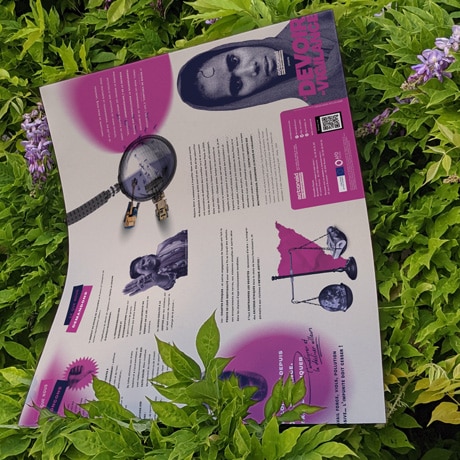Une brochure sur le devoir de vigilance en couleurs violet et rose repose sur un lit de feuilles vertes et de lilas. La brochure présente des textes et des images, y compris des portraits de personnes et des infographies. Le cadre naturel et la brochure créent un contraste entre le matériel éducatif et l'environnement organique.